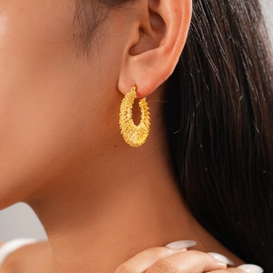 Close-up of 18k gold plated braided hoop earring worn on a model for a vintage look