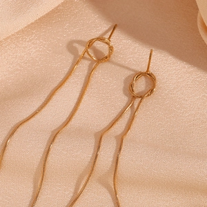 Detailed macro view of long 18K gold-plated snake chain tassels and a knotted metal ring