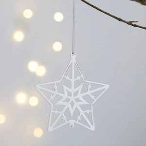 Ornement de Noël en étoile de fer suspendu à une branche avec fond lumineux bokeh