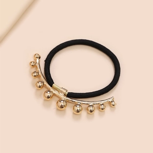 Detail of black elastic hair tie featuring a golden metallic arc with gold beads