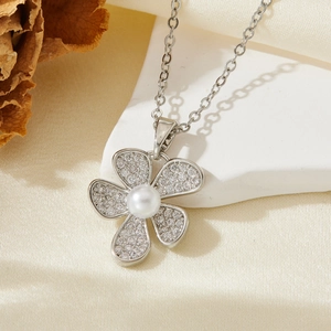 Gros plan d'un pendentif fleur en argent avec cristaux micro-pavés et une perle blanche