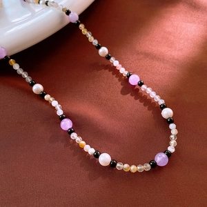 Détail d'un collier de perles colorées avec pierres naturelles sur tissu en soie