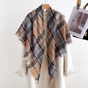 Detailed view of the plaid scarf with fringe edges draped over a white coat on a hanger