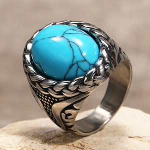 Macro shot of vintage signet ring with large turquoise stone and woven metal texture
