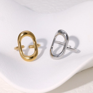 Close-up of hollow geometric rectangle ring in gold and silver on white ceramic tray