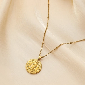 Detailed close-up of a gold embossed coin pendant on a beaded chain over silk fabric