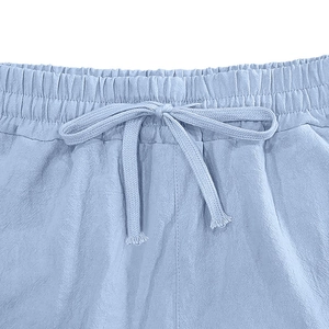 Detailed macro view of light blue linen pants featuring elastic waistband and drawstring