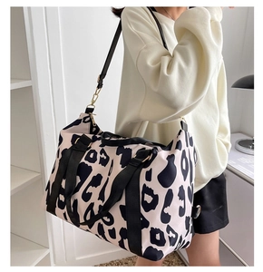 Close-up of waterproof cow print travel tote showing shoulder strap and gold hardware