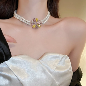 Detail einer zweilagigen Perlen-Choker-Kette mit rosa und gelbem Kristallblumen-Anhänger