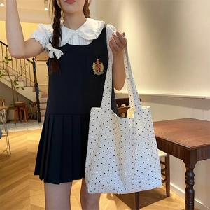 Polka dot canvas tote bag held by a model in a minimalist indoor lifestyle setting