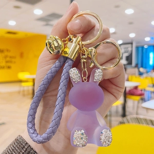 Close-up of a purple resin rabbit keychain with diamond-studded ears and a gold bell