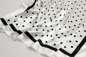 Detail showing white silk scarf with black polka dots and striped border texture
