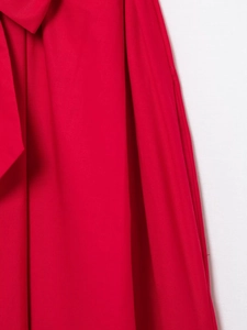 Detailed macro shot showing red poplin fabric texture and fine stitching on the dress