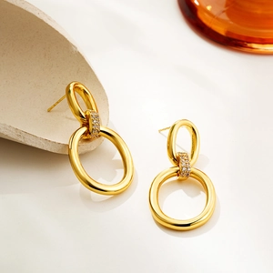 Detail of 18K gold-plated double-loop earrings with zircons on a minimalist stone base
