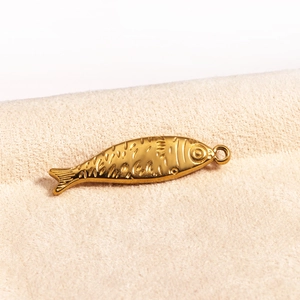 Detailed macro view of a golden metal fish pendant with fine scales and eye textures