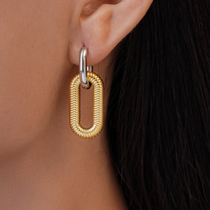 Close-up of two-tone oval textured earrings in gold and silver finish on a model