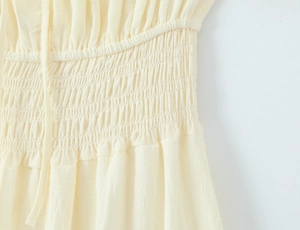 Detail der gerafften Taille und Leinenstruktur auf einem cremefarbenen Kleid