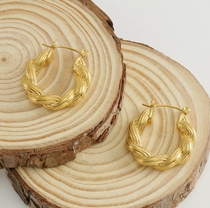 Detailed view of 18k gold plated twisted rope hoop earrings on a natural wood surface