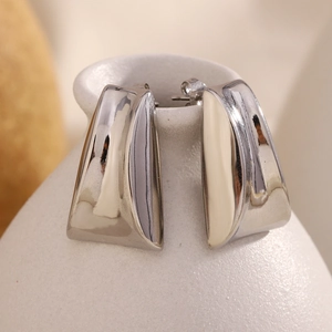 Macro detail of silver trapezoid earrings in 316L stainless steel on ceramic vase