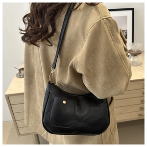Detail of black vintage underarm bag with gold hardware and front snap pocket worn by model