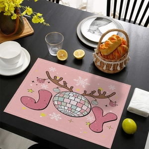 Pink rectangular Christmas placemat with JOY reindeer design on black wooden table