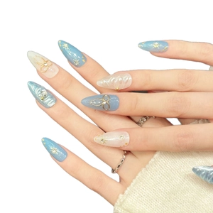 Handmade press-on nails with blue-white gradient, golden bows, and glitter rhinestones