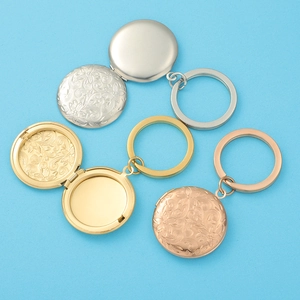 Detailed view of floral embossed photo locket keychains in gold, silver, and rose gold