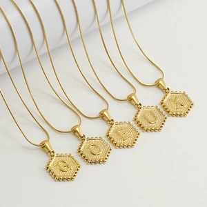 Colliers en chaîne serpent dorée avec pendentifs hexagonaux à lettres sur supports blancs