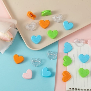 Close-up of colorful heart-shaped plastic clips on a notebook and pastel backgrounds