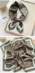 Detailed view of olive paisley silk square scarf showing print patterns and folded texture