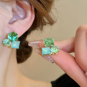 Détail de boucles d'oreilles florales avec pierres bleues et vertes et monture dorée
