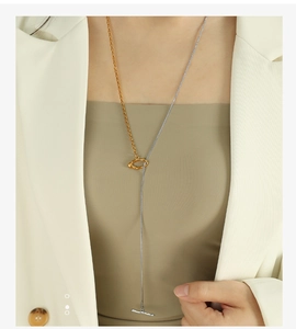 Detail of mixed-metal OT buckle necklace with gold ring and silver snake chain on model