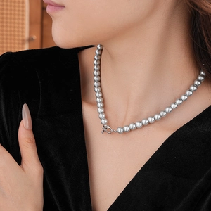 Detailed close-up of grey pearl necklace with rhinestone OT clasp on a model