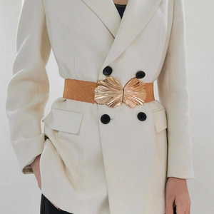 Eleganter elastischer Gürtel mit goldener Blattschnalle auf einem weißen Blazer