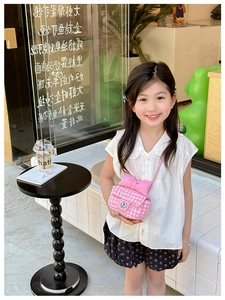 Pink checkered girl's crossbody bag with bow detail and chain strap on a child model