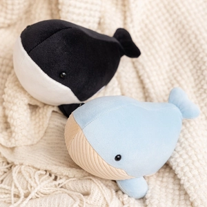 Plush whale toys in black and blue colors on a soft knit blanket background