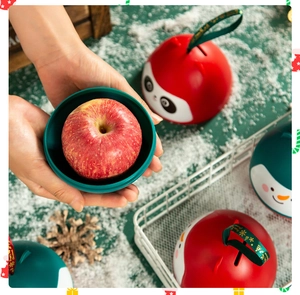 Close-up of spherical Christmas apple gift box with Merry Christmas ribbon and snow scene