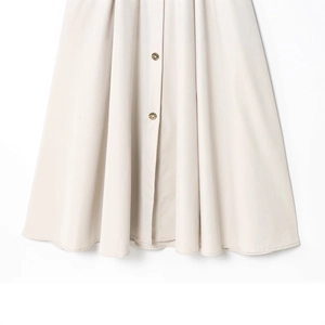 Fashionable beige patchwork dress featuring pleated hem and decorative golden buttons