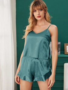 Detailed macro view of silky peacock green satin pajamas with elegant ruffle trim