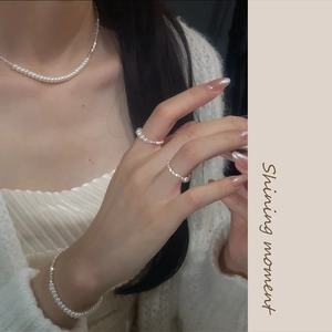 Detail shot of the elegant pearl jewelry set worn by a model including a necklace and ring