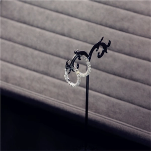 Close-up of oversized silver hoop earrings with sparkling crystals on a black stand
