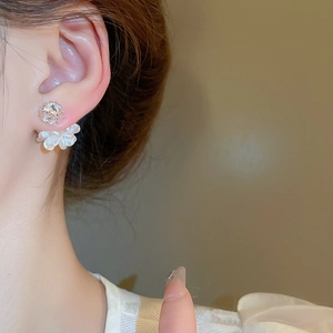 Nahaufnahme von eleganten Kamelien-Perlenohrringen mit Zirkon am Ohr des Models