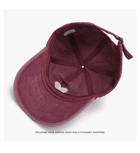 Detail view of burgundy baseball cap interior with white heart embroidery and label