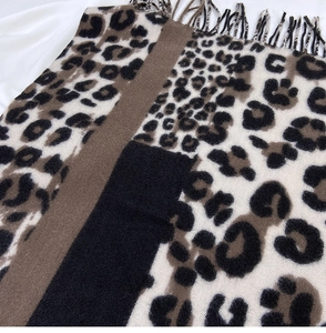 Detail of leopard print scarf featuring thick cashmere-like fabric and long fringe edges