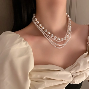 Close-up of multilayer pearl necklace with gold square beads and white round pearls
