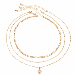 Detailed view of triple-layered gold necklaces with rhinestone pendants and Figaro chain