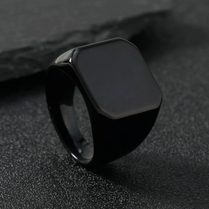 Macro shot of polished black titanium steel square signet ring on textured stone