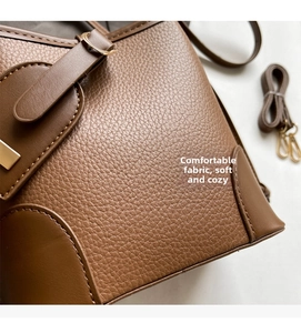Close-up of brown litchi pattern leather bag showing fine stitching and gold buckle