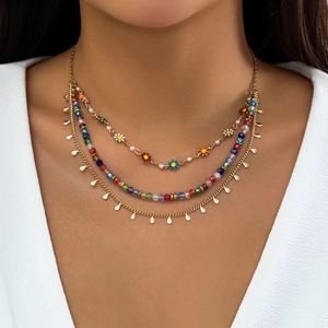 Close-up of layered necklace with colorful beads, floral charms and golden teardrop sequins