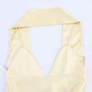 Detail eines hellgelben Satin-Oberteils mit glänzendem Stoff und Neckholder-Ausschnitt